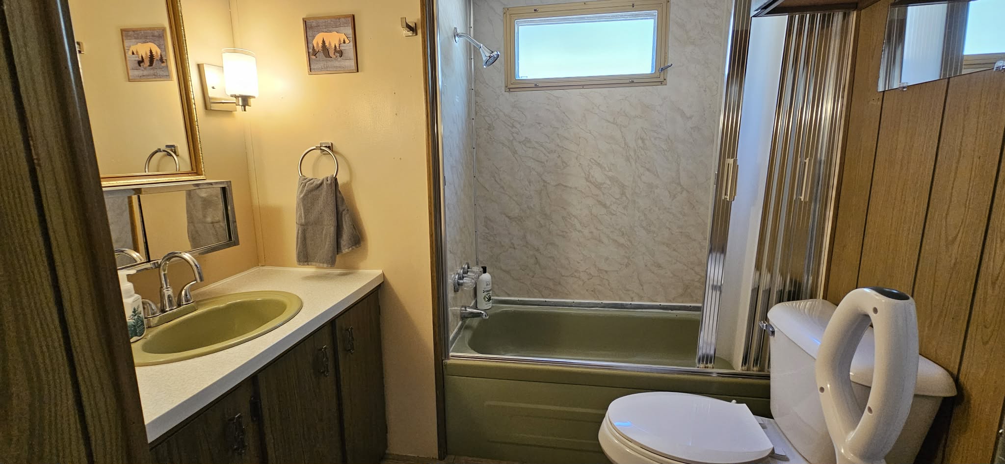 Clean and functional bathroom featuring a sink with mirror, tiled shower enclosure, and bright lighting, providing essential amenities in a well-maintained cabin environment